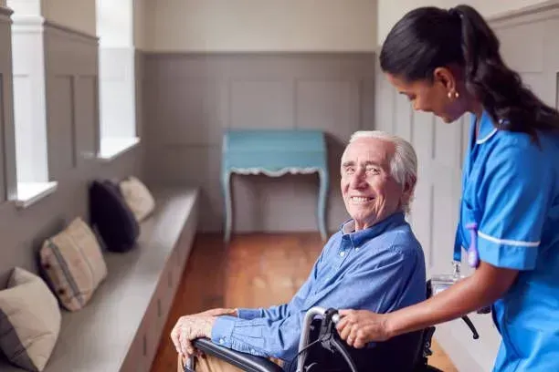 A nurse is helping an elderly man in a wheelchair.
