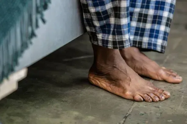 A person wearing plaid pajamas is standing next to a bed.