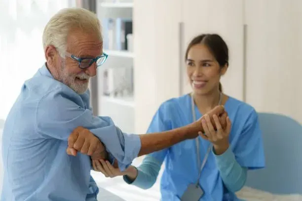A nurse is helping an elderly man stretch his arms.