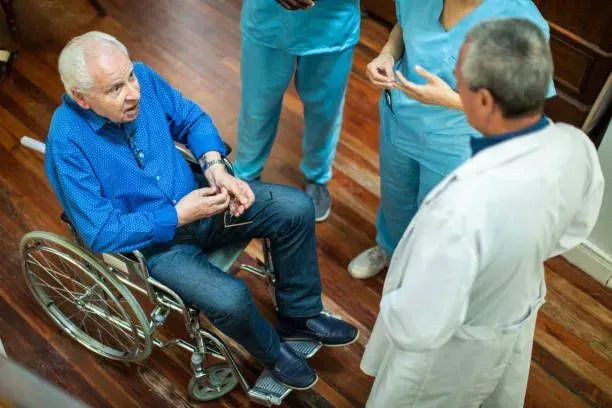 A man in a wheelchair is talking to a doctor and nurse.