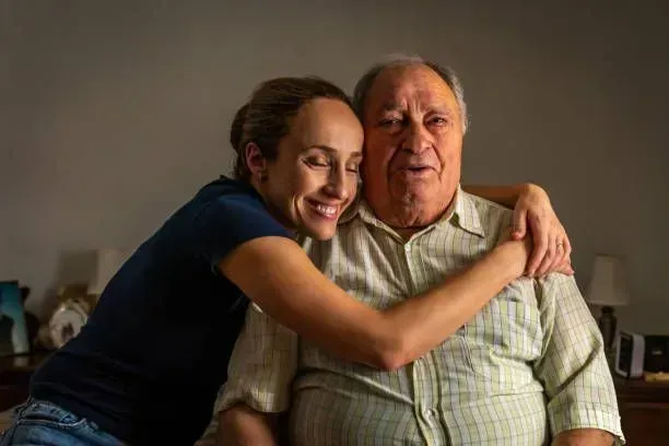 A woman is hugging an older man in a room.