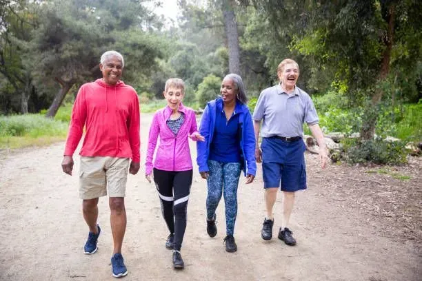 A group of people are walking down a dirt path in the woods.