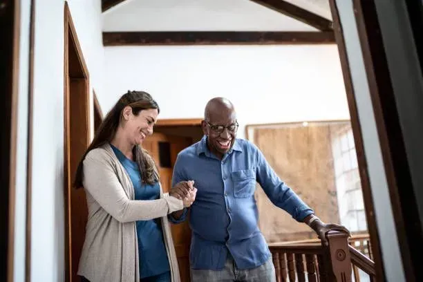 A woman is helping an older man walk up the stairs.