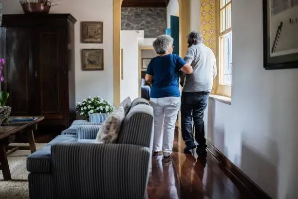 A man and a woman are walking down a hallway in a living room.