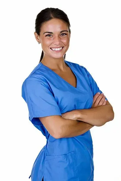 A woman in a blue scrub is smiling with her arms crossed