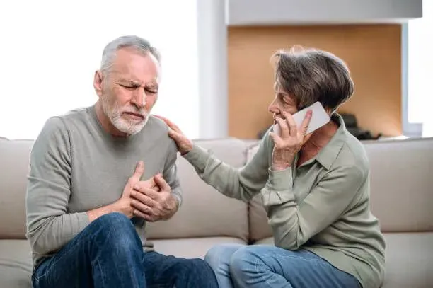 A woman is talking on a cell phone while a man has a heart attack.