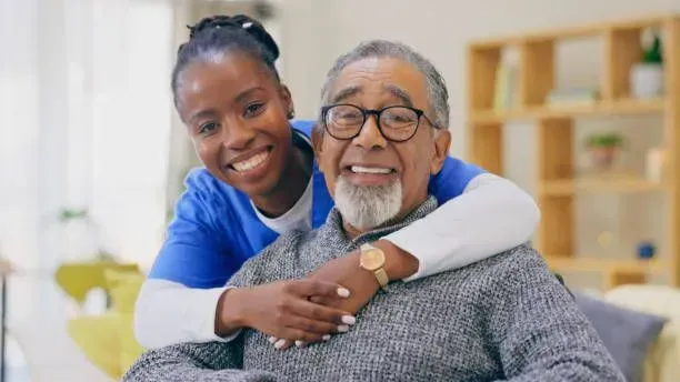 A nurse is hugging an elderly man in a wheelchair.