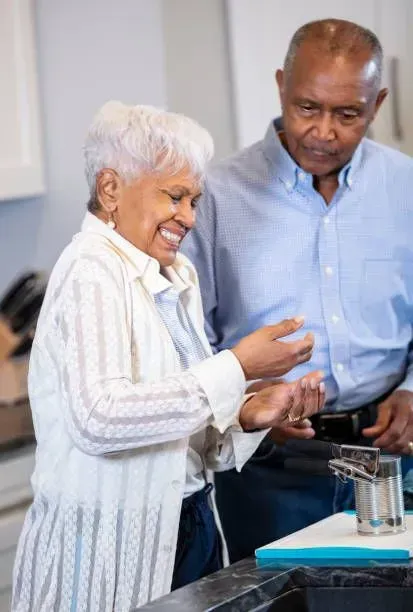 A man and a woman are standing next to each other in a kitchen.