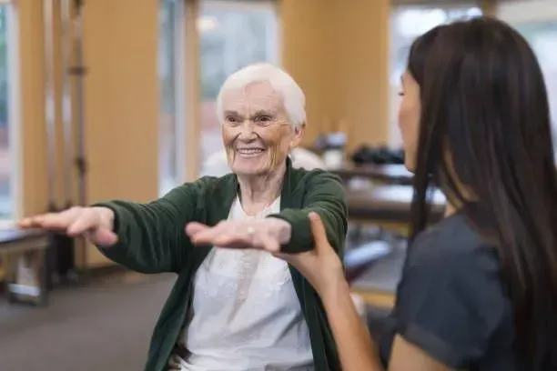 An elderly woman is doing exercises with a nurse.