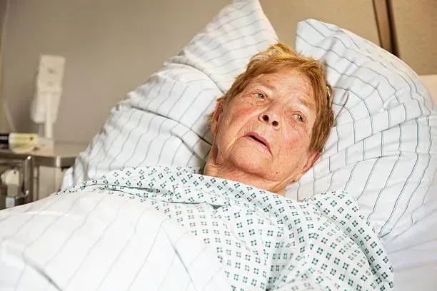 An elderly woman is laying in a hospital bed.
