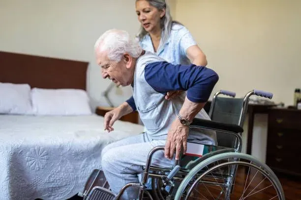 A woman is helping an elderly man in a wheelchair.