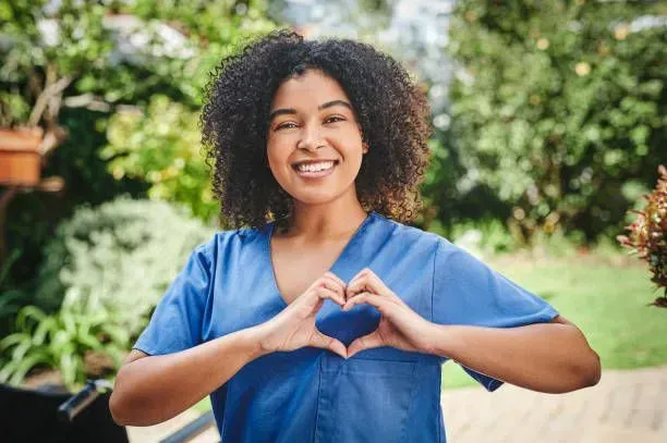 A nurse is making a heart shape with her hands.