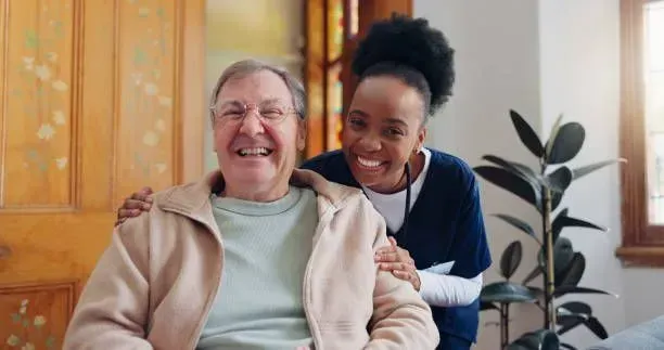 A nurse is putting her arm around an elderly man in a wheelchair.