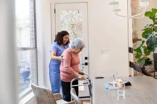 A nurse is helping an elderly woman with a walker.