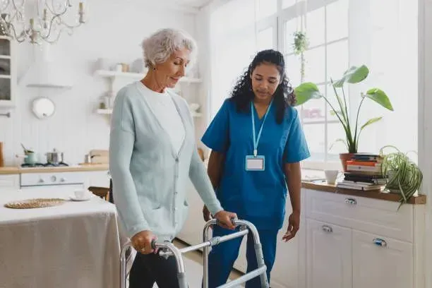 A nurse is helping an elderly woman walk with a walker.