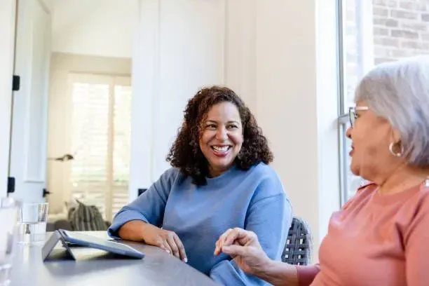 Two women are sitting at a table talking to each other.