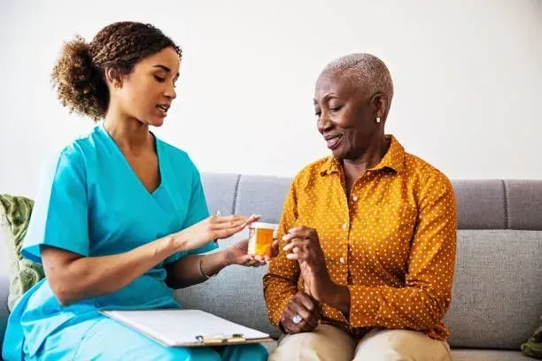 A nurse is giving an elderly woman a bottle of pills.