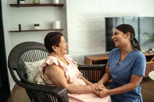 A nurse is holding the hand of an elderly woman who is sitting in a chair.