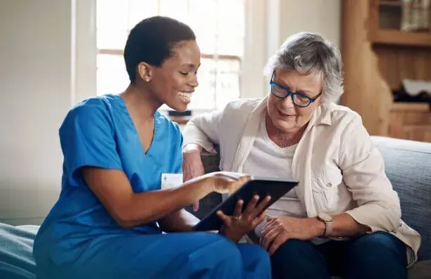 A nurse is showing an elderly woman how to use a tablet computer.