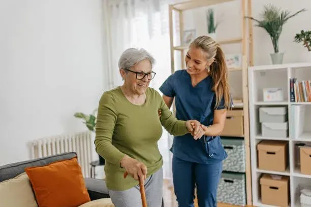 A nurse is helping an elderly woman walk with a cane.
