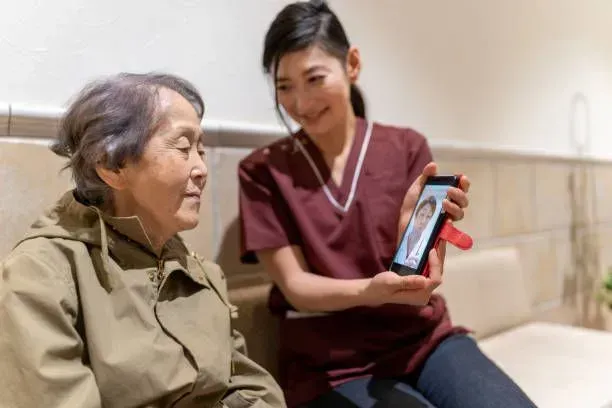 A nurse is holding a cell phone in front of an elderly woman.