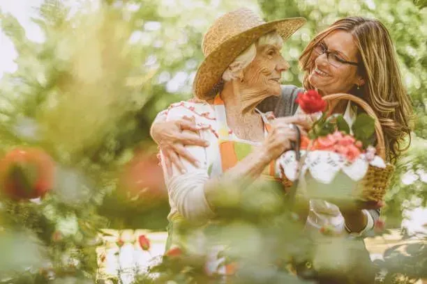 A woman is holding a basket of flowers and hugging an older woman.