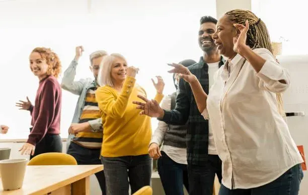 A group of people are dancing together in an office.