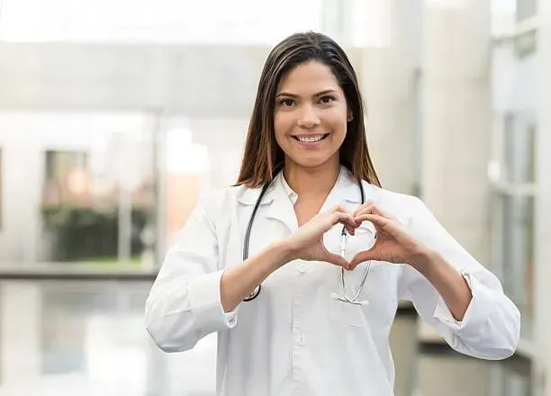 A female doctor is making a heart shape with her hands.