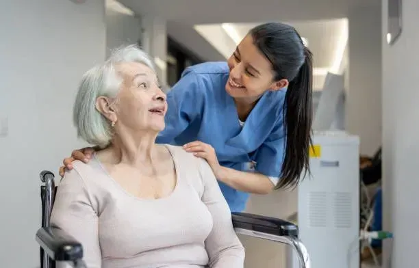 A nurse is talking to an elderly woman in a wheelchair.