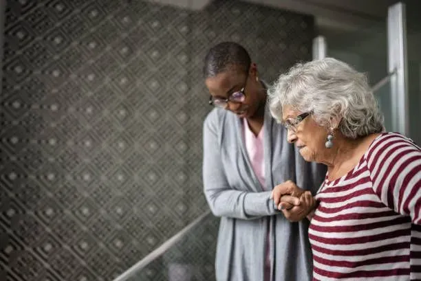 A woman is helping an older woman walk down the stairs.