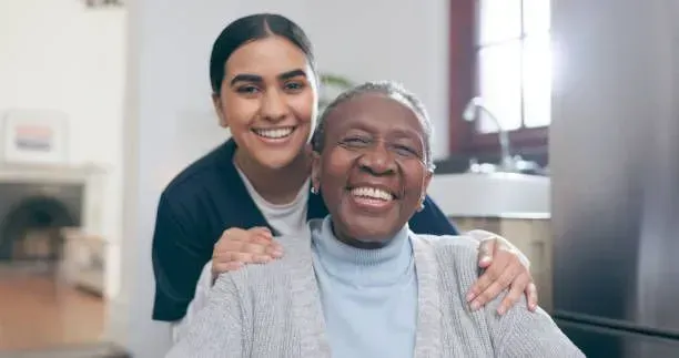 A young woman is hugging an older woman in a wheelchair.