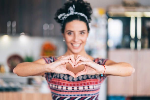 A female home health aide is making a heart shape with her hands.