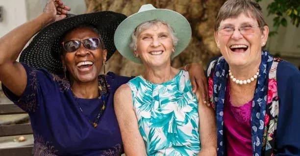 Three older women are posing for a picture together and laughing.
