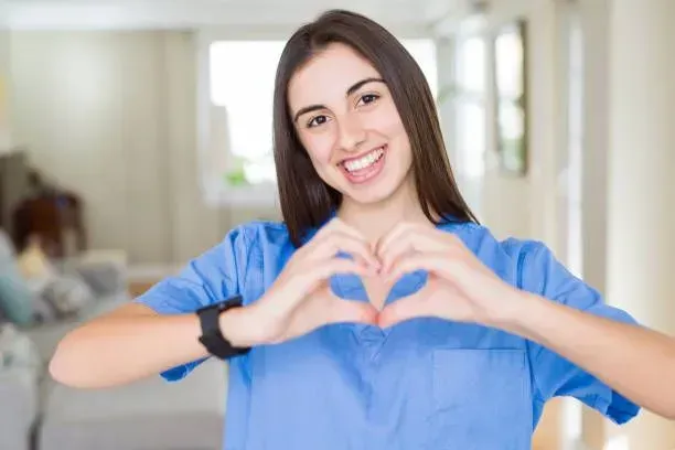 A nurse is making a heart shape with her hands.