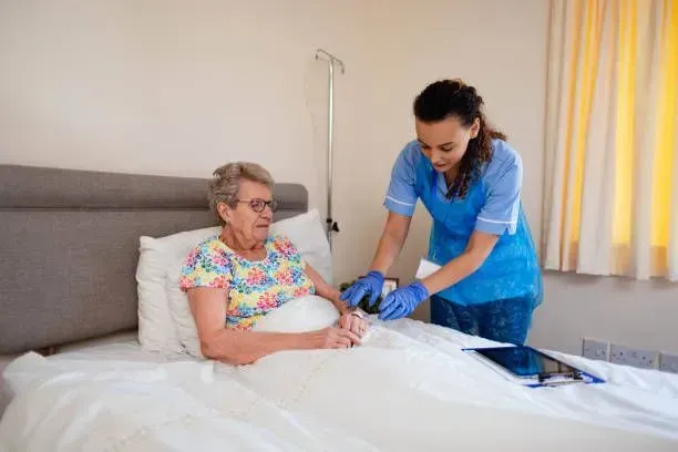 A nurse is helping an elderly woman in a hospital bed.
