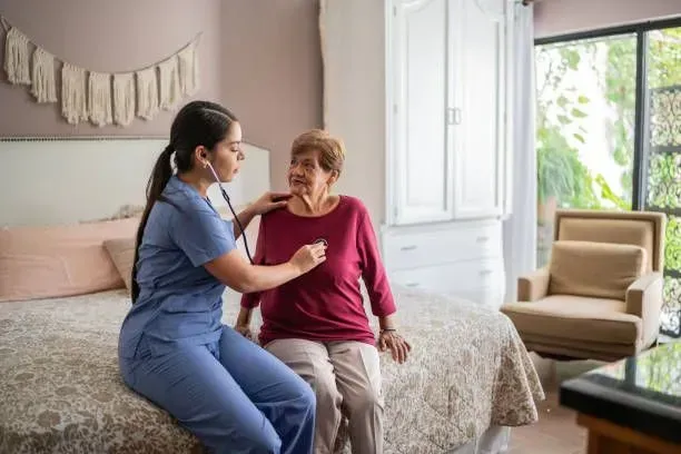 A nurse is listening to an elderly woman 's heartbeat with a stethoscope.