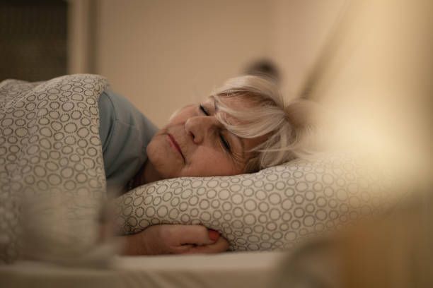 A woman is sleeping in a bed with a pillow and a blanket.