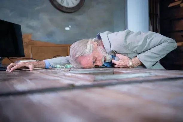 An elderly man is laying on a wooden table.