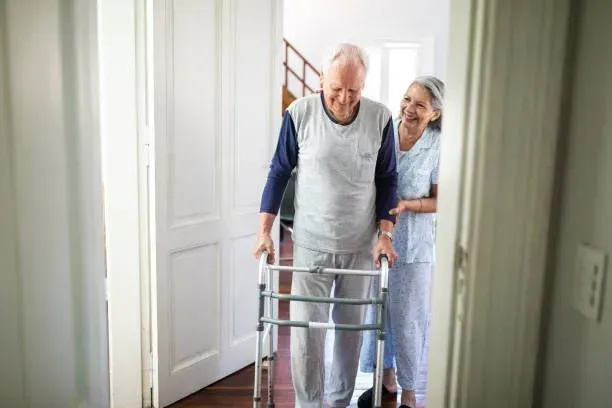 An elderly man with a walker is being helped by a nurse.