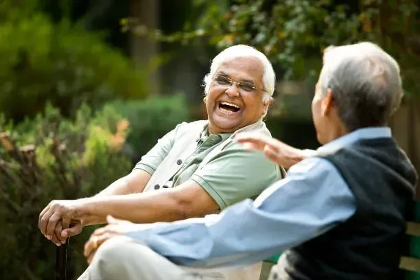 A man and a woman are sitting on a bench laughing.