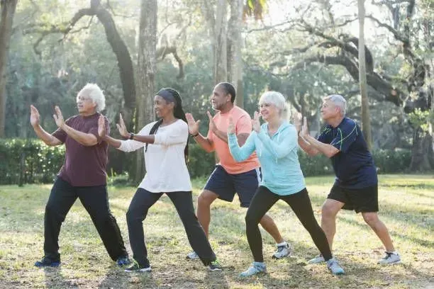 A group of older people are practicing tai chi in a park.