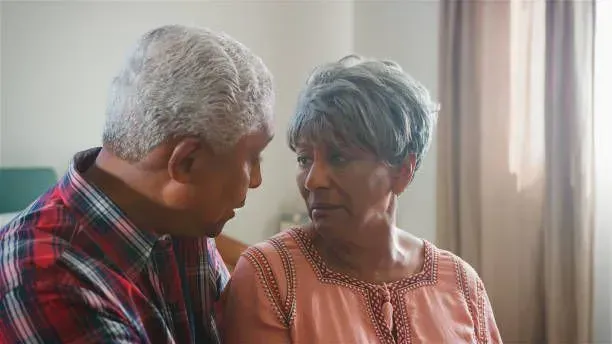 A man and a woman are looking at each other in a living room.