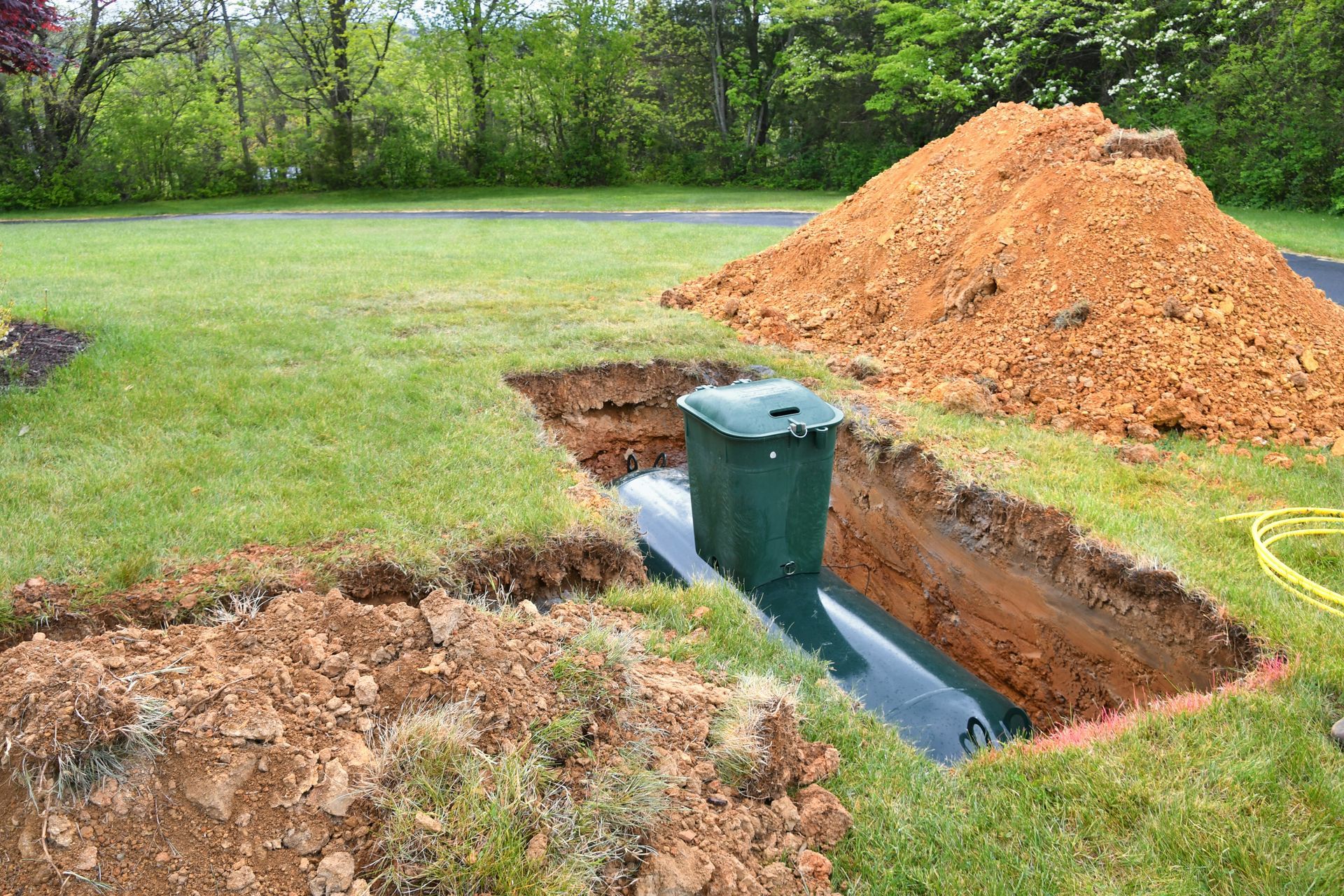 Septic tank installation in rural yard with trench excavation and soil pile during system replacemen