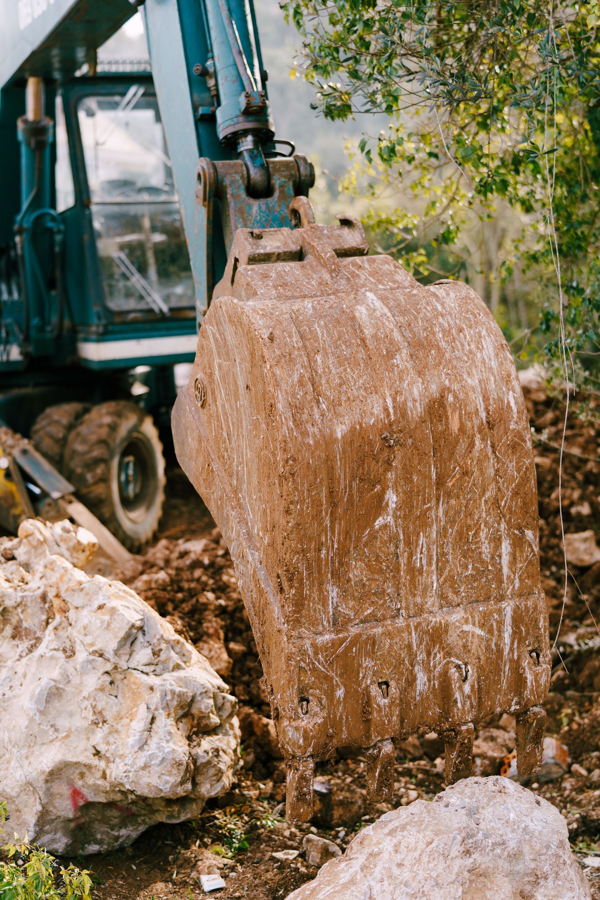 Excavator bucket dumping dirt and rocks at a construction site