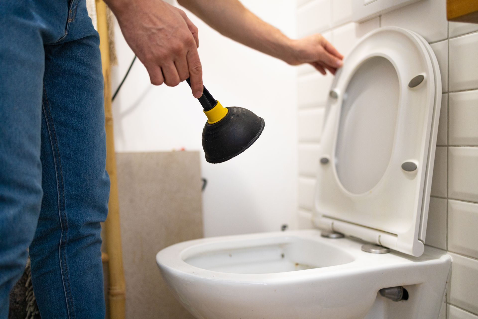 Man using a plunger on a toilet while checking a plumbing problem in a Houston, Missouri home.