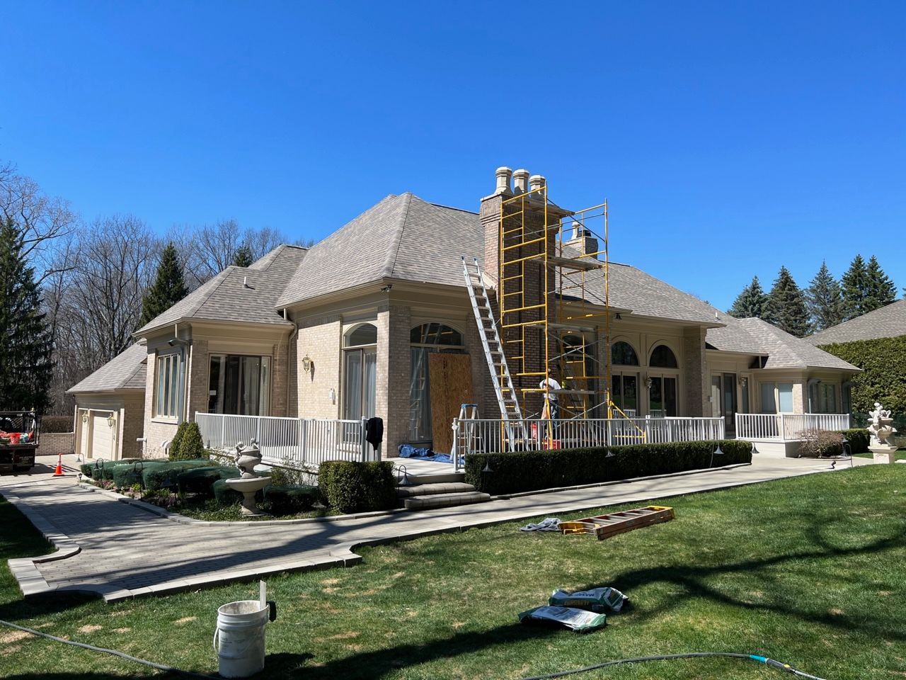 Single-story house under construction with scaffolding and a ladder in front yard