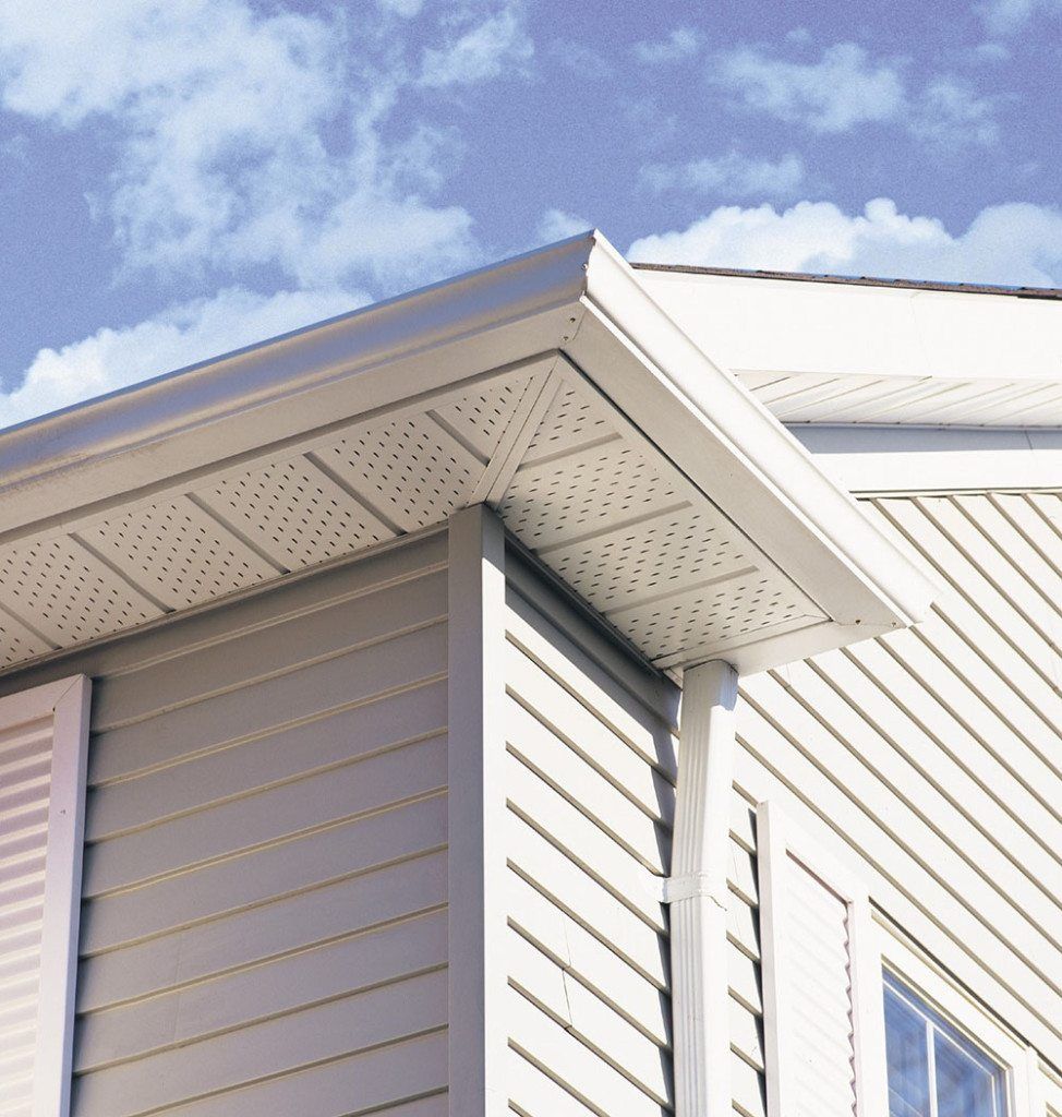Close-up of a white house exterior with vinyl siding, soffit vents, and a gable roof against a blue sky.