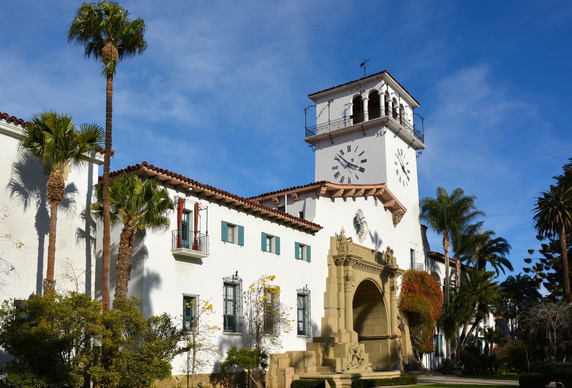 A large white building with a clock tower and palm trees in front of it