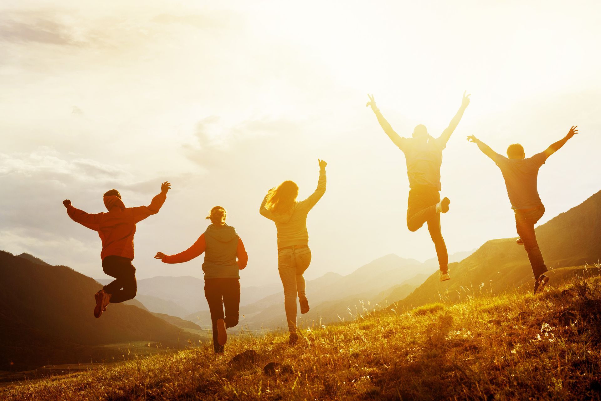 A group of people are jumping in the air in the mountains.