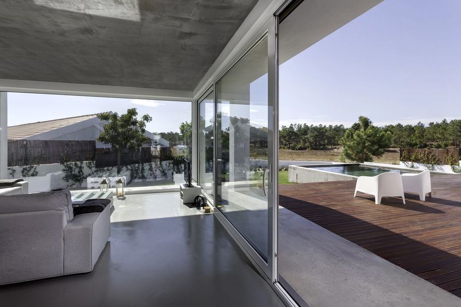 Patio moderno con porte a vetri, divano bianco e posti a sedere in terrazza con vista su un paesaggio soleggiato.